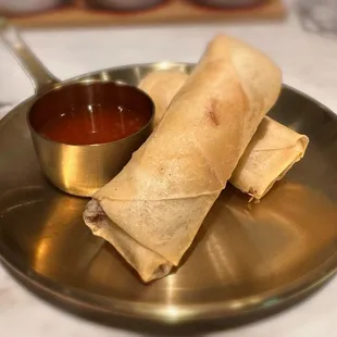 two burritos on a plate with dipping sauce