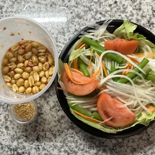 a bowl of salad and a container of peanuts