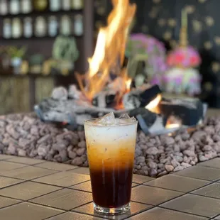 a cold drink on a table in front of a fire pit