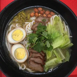 a bowl of ramen with meat, eggs, and vegetables