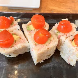 a plate of sushi with cherry tomatoes