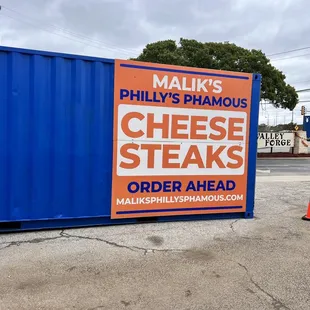 a sign in front of a blue shipping container
