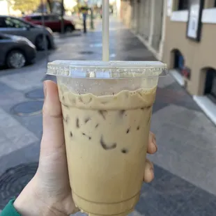 a hand holding a cup of iced coffee