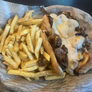 Philly's steak cheese, steamed onion, mushrooms, sandwich with fried fries.