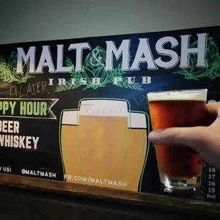 a hand holding a pint of beer