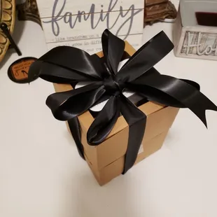 a brown gift box with a black ribbon