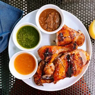 a plate of grilled chicken with dipping sauces
