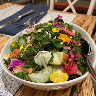 a salad in a white bowl on a wooden table