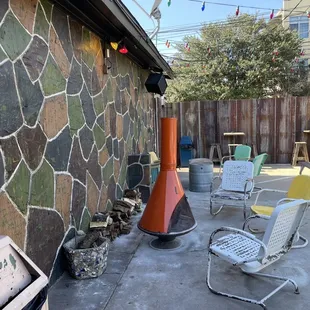 a patio with a fire pit and chairs
