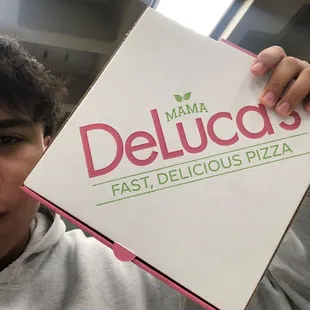 a man holding a box of delucaccis