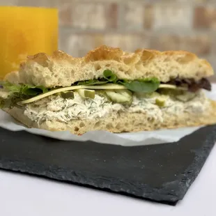 a chicken salad sandwich with a glass of orange juice