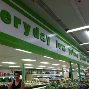 a woman standing in front of a display of vegetables