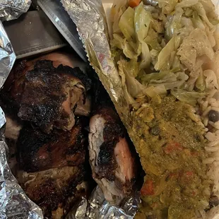 Jerk chicken dinner with and peas and cabbage and jerk sauce on the side