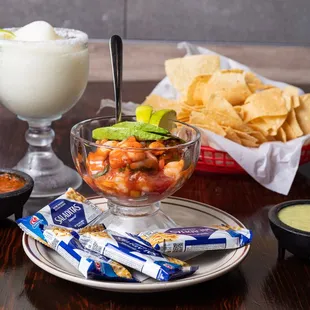 a bowl of chips, salsa, and a glass of margarita