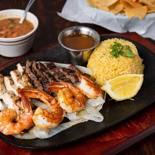 a plate of grilled shrimp, rice, and chips