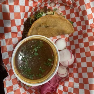 Quesa birria taco and consomé with sliced radishes and pickled red onions.