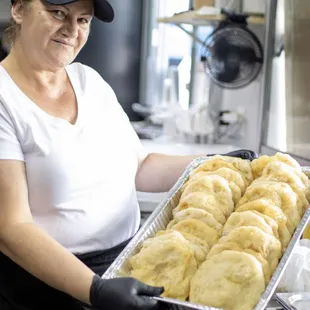 a woman holding a tray of freshly made doughnuts