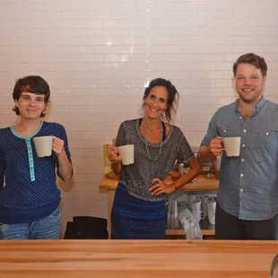 three people holding coffee mugs
