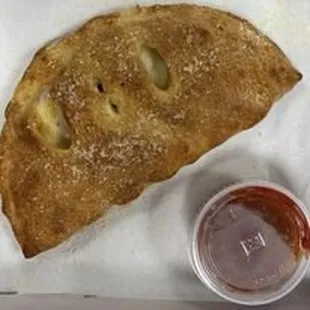 a piece of pizza and a cup of ketchup