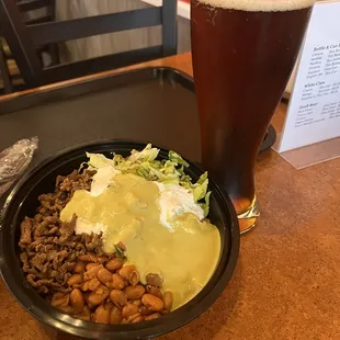 a bowl of beans, rice, and a beer