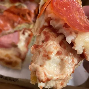 a hand holding a slice of pizza