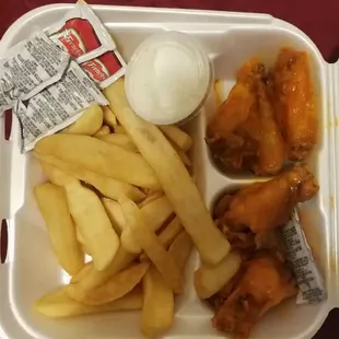 chicken wings and fries in a styrofoam container