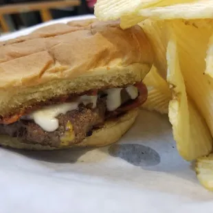 Pizza burger with a side of potato chips.