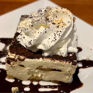 a piece of cake with whipped cream and chocolate sauce