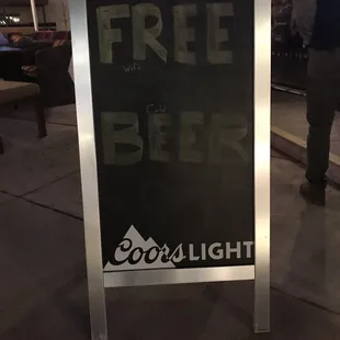 a free beer sign on a sidewalk