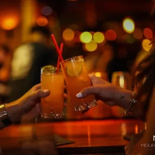 two people toasting drinks at a bar