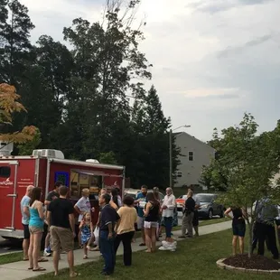 a group of people standing outside of a food truck