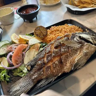 a plate of fish with rice and vegetables