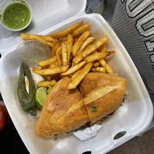 a sandwich and fries in a styrofoam container