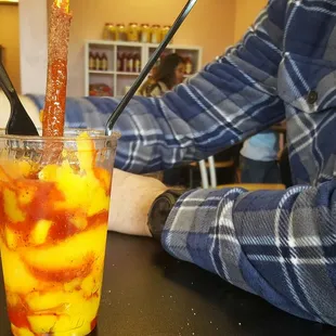Mangonada. mango, chili sauce, mango sherbert, straw with chili candy