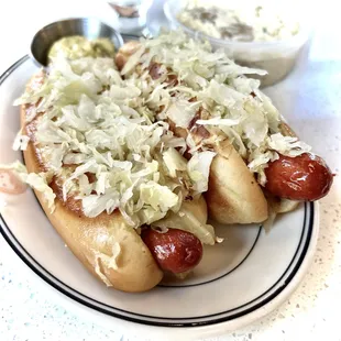 two hotdogs with sauerkraut and coleslaw