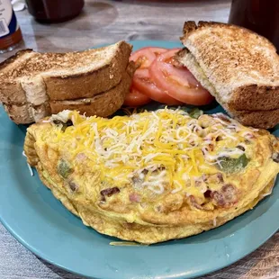 Kitchen Sink omelette with wheat toast and sliced tomatoes.