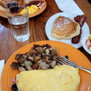 Omelet, breakfast potatoes, pancakes, fresh fruit, bacon.