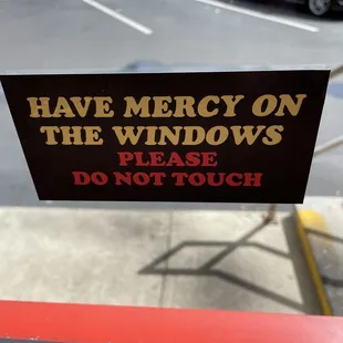 a sign that says have mercy on the windows please don&apos;t touch