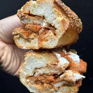 a hand holding a half eaten sandwich