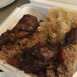 Brown stew chicken with rice and peas and cabbage on the side.