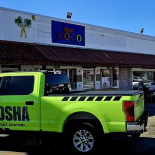a bright green truck parked in front of a business