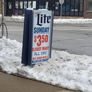 a sign on a snowy sidewalk