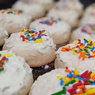 a close up of a tray of cookies with frosting and sprinkles