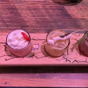 three different drinks on a wooden tray