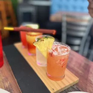 a wooden tray with two cocktails on it