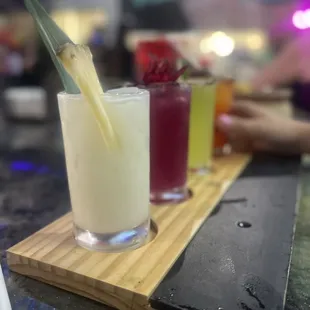 a variety of cocktails on a wooden tray