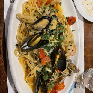a plate of pasta with musselling and shrimp