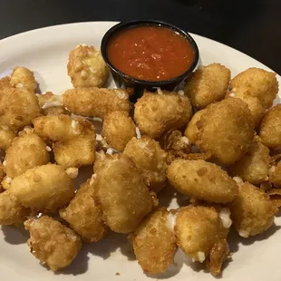 a plate of fried tater tots with a side of tomato sauce