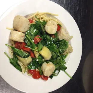 a plate of pasta with spinach and scallops
