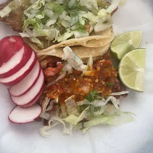 Fish taco (lettuce on top) and Al pastor taco (red salsa) with limes and radishes